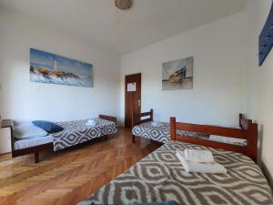 a room with two beds and a wooden floor at PORTA NOVALIS Rooms in Novalja