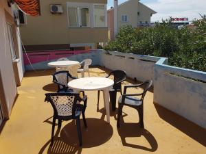 a group of tables and chairs on a balcony at PORTA NOVALIS Rooms in Novalja
