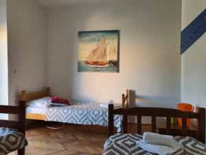 a bedroom with two beds and a painting of a sailboat at PORTA NOVALIS Rooms in Novalja