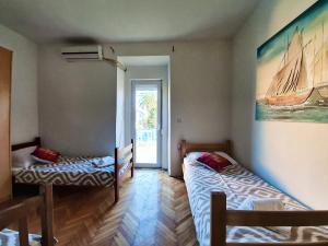 a room with two beds and a painting of a boat at PORTA NOVALIS Rooms in Novalja +19 photos