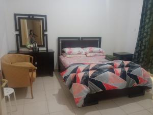 ein Schlafzimmer mit einem Bett, einem Stuhl und einem Spiegel in der Unterkunft Furnished room in a villa in town center. With private bathroom in El Ain