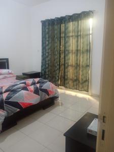 sypialnia z łóżkiem i oknem z zasłonami w obiekcie Furnished room in a villa in town center. With private bathroom w mieście El Ain