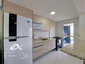 eine Küche mit einem weißen Kühlschrank und einer Spüle in der Unterkunft Apartamento perto da praia no Indaiá in Bertioga