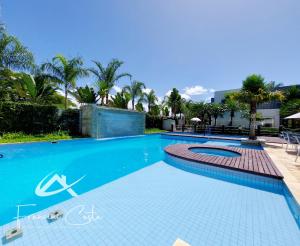 einen Pool in einem Resort mit Palmen in der Unterkunft Apartamento perto da praia no Indaiá in Bertioga