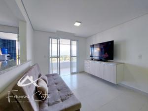 ein Wohnzimmer mit einem Sofa und einem Flachbild-TV in der Unterkunft Apartamento perto da praia no Indaiá in Bertioga
