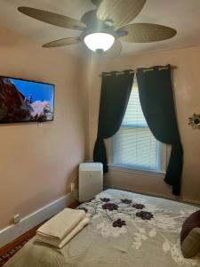 a bedroom with a bed with a ceiling fan and a window at 2BR-Free parking, Near Gillette & Providence-I-95 in Pawtucket