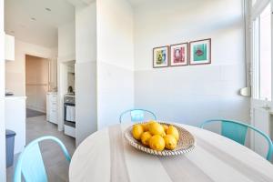 a white kitchen with a table with a bowl of fruit at Quiet and Central 2BR APT, By TimeCooler in Lisbon