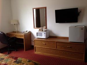 Cette chambre d'hôtel dispose d'une télévision et d'une commode avec un four micro-ondes. dans l'établissement Budget Host Caribou Inn, à Hallock