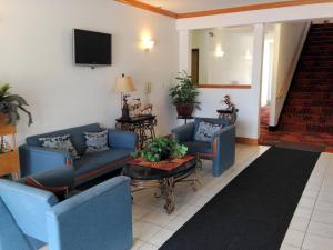 een woonkamer met blauwe banken en een tv bij Budget Host Caribou Inn in Hallock