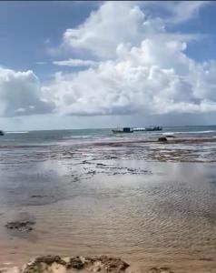 a beach with a cloudy sky and the ocean at Praia do Forte Kauai Bahia in Praia do Forte