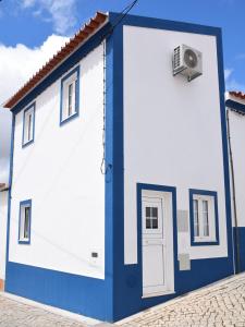 a blue and white building with a door and a fan at Casinha da Esquina in Amieira