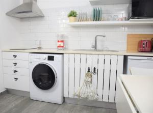 a kitchen with a washing machine and a sink at Casinha da Esquina - Refúgio Alentejano a 700m da Praia in Amieira