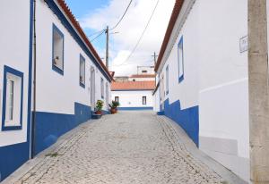 an alley in a town with blue and white buildings at Casinha da Esquina in Amieira