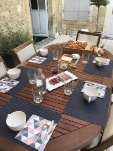 a wooden table with plates and bowls on it at Chambre Alix in La Flèche