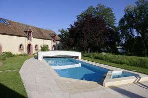 a swimming pool in a yard next to a house at Le Clos Bener in Yvré-lʼÉvêque