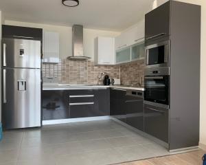 a kitchen with stainless steel appliances and black cabinets at Baby’s Apartment in Skopje