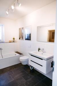 a white bathroom with a sink and a tub and a toilet at Haus am Diemelufer - Natur pur, private Sauna - der Luxus der Stille in Heringhausen +23 photos