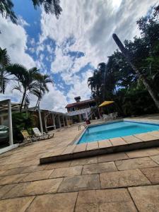 a swimming pool with chairs and a house with a sky at Suites Geriba in Búzios