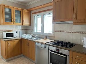a kitchen with wooden cabinets and a stove top oven at Zulla Moradia T3, Praia do Norte in Nazaré