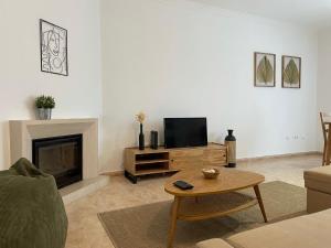 a living room with a fireplace and a tv at Zulla Moradia T3, Praia do Norte in Nazaré
