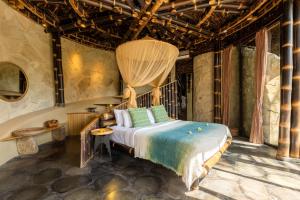 ein Schlafzimmer mit einem Bett in einem Zimmer mit Steinwänden in der Unterkunft Eclipse House 4bds Eco Bamboo House Pool RiverView in Bringkit