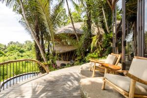 eine Veranda mit Stühlen und ein Haus mit Palmen in der Unterkunft Eclipse House 4bds Eco Bamboo House Pool RiverView in Bringkit