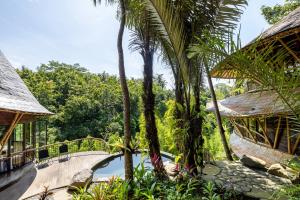 eine Brücke über einen Pool in einem Resort mit Palmen in der Unterkunft Eclipse House 4bds Eco Bamboo House Pool RiverView in Bringkit