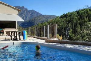 una persona nadando en una piscina con montañas en el fondo en CASA SAPEIRÓ - Allotjament Rural en Cellers