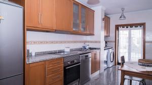 a kitchen with wooden cabinets and a sink and a refrigerator at Casa Miguelito in Aveiro