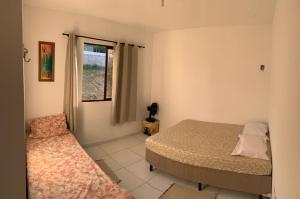 Schlafzimmer mit einem Bett und einem Fenster in der Unterkunft Duplex com 02 Suítes e Ar-Condicionados in Bananeiras