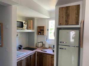La cuisine est équipée d'un réfrigérateur blanc et de placards en bois. dans l'établissement Bel appartement idéalement situé en Haute Corse, à Lumio