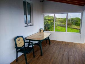 a dining room with a table and two chairs and a window at Casa do Marcelino Lagarto in São Roque do Pico