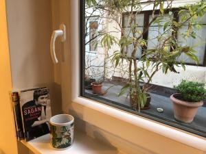 um peitoril de janela com um livro e um copo e plantas em Cité Pilleux - Charming Studio in a flowery pedestrian lane em Paris