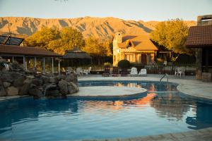 a swimming pool with a house and mountains in the background at La Quinta Resort in Merlo