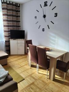 a living room with a table and a clock on the wall at Apartament ADA in Koszalin
