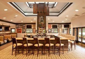 a restaurant with a large bar with chairs around it at Sonesta Atlanta Airport South in Atlanta