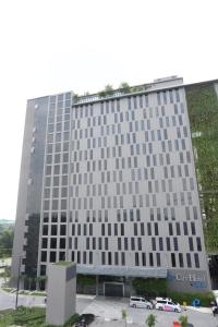 um edifício alto com carros estacionados em frente em e.City Hotel@OneCity em Subang Jaya