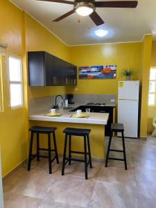 uma cozinha com paredes amarelas e um balcão e bancos em Posada Paraiso em El Yaque
