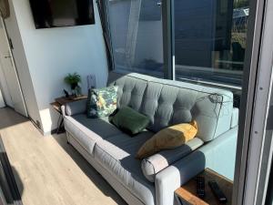 a gray couch in a room with a window at Waterfront houseboat in Monnickendam near the centre in Monnickendam