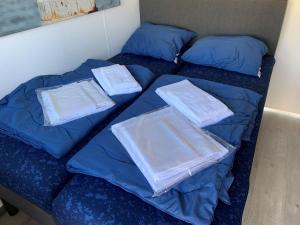 Una cama con sábanas azules y almohadas. en Waterfront houseboat in Monnickendam near the centre, en Monnickendam