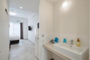 a white bathroom with a sink and a bedroom at BiBi Hotel Naminoue in Naha