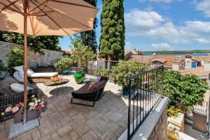 a patio with an umbrella and chairs and a table at Luxury Villa Orh Rovinj in Rovinj