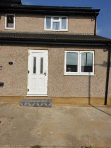 a house with a white door and two windows at Two beautiful double bedroom Tulip apartment in Dagenham