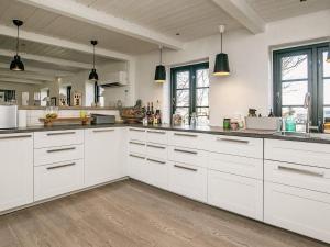 una gran cocina blanca con armarios blancos y ventanas en Holiday home Løkken CLXVI, en Løkken