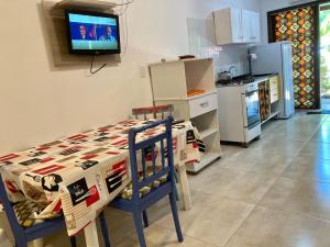 Casa Foca في بومبينهاس: مطبخ مع طاولة وتلفزيون على الحائط