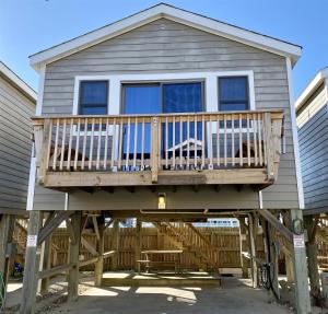 a house with a deck with a dog on it at NC 12 56821-10 Condo in Hatteras
