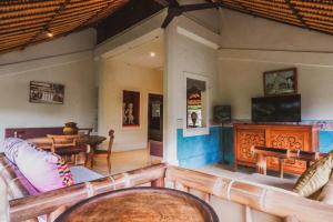 a living room with chairs and a television and a table at Bebek Cottages Sanur in Sanur