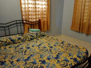ein Schlafzimmer mit einem Bett mit einer blauen und gelben Decke in der Unterkunft Rumah Tamu Pekan (semi D) in Pekan