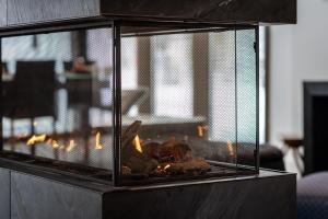 una chimenea con carne y llamas. en Nordic Lodge Tremblant -5 Bdrs,hot Tub,pool Table, en La Conception