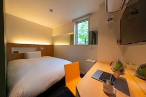 Schlafzimmer mit einem Bett und einem Schreibtisch mit einem Laptop in der Unterkunft Kamishihoro Hotel in Kami-shihoro